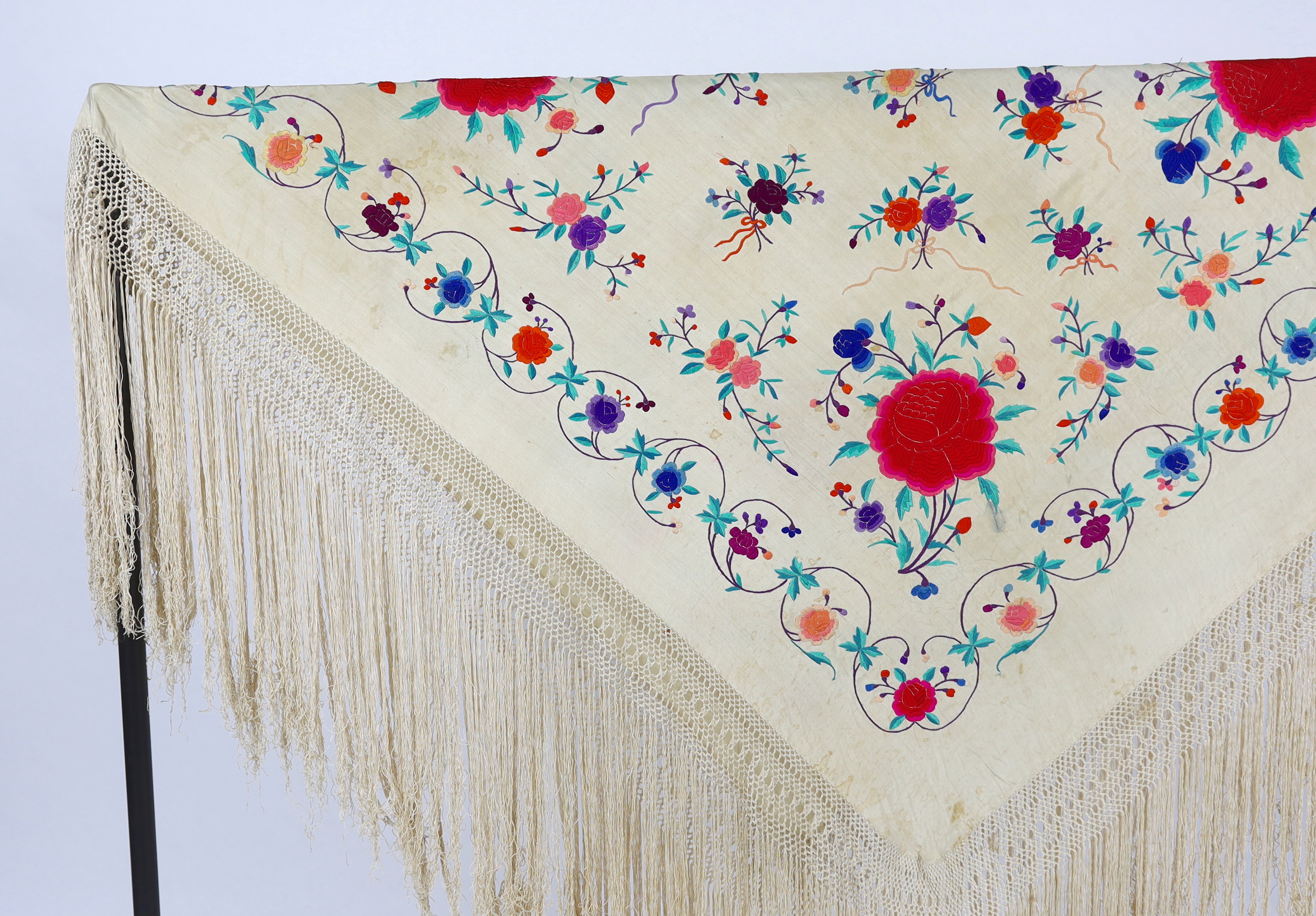 A late 19th / early 20th century cream silk fringed shawl, embroidered with all over polychrome silk floral motifs, 130 x 150cm not including fringe